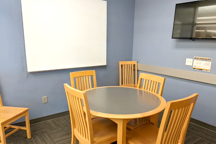 Photograph of a small study room showing whiteboard, LCD screen and furniture arrangement